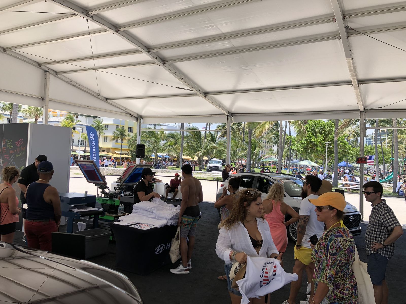 Guests gathering around a personalization station under a large white tent at an outdoor corporate event